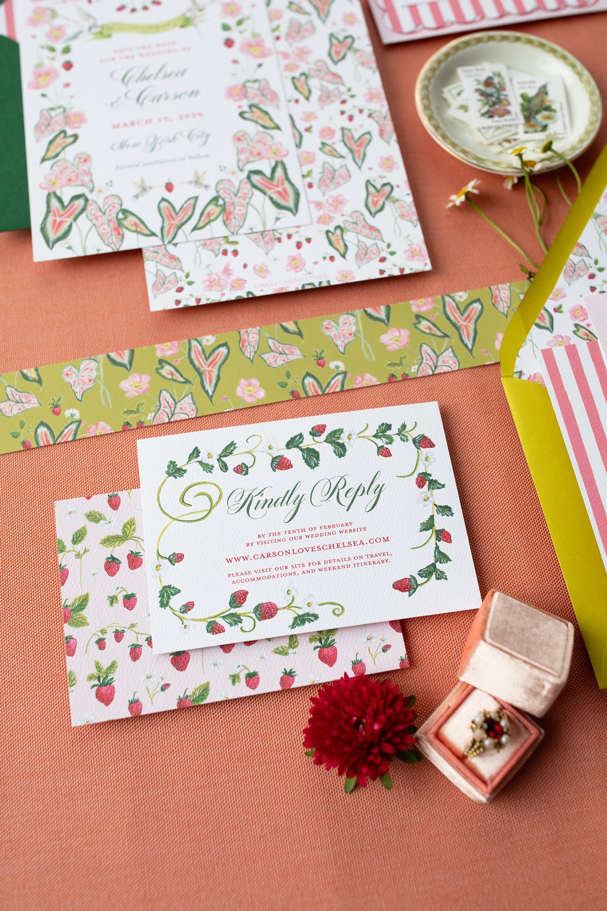 Floral and strawberry-themed stationery items on a pink surface