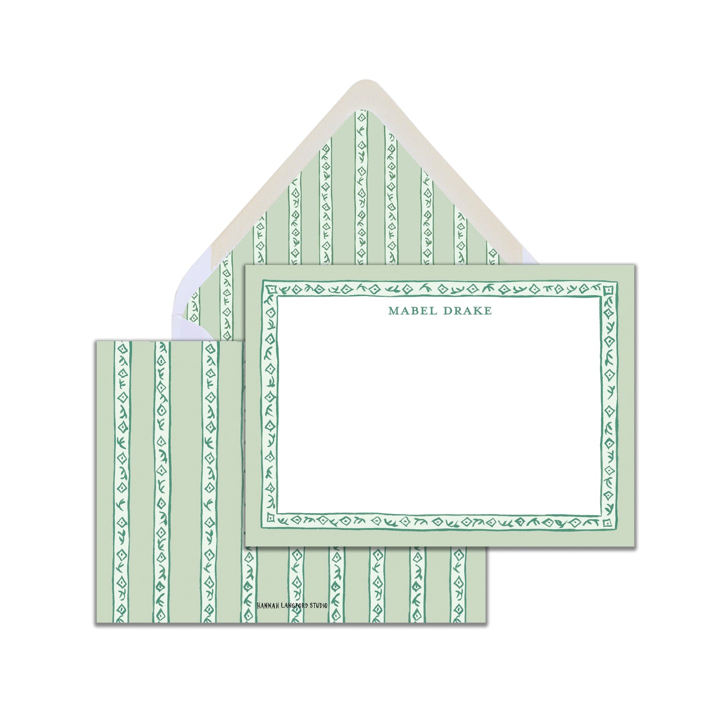 A set of sage green block-printed stationery cards with a name personalized on the front and a coordinating pattern on the back, accompanied by white envelopes.