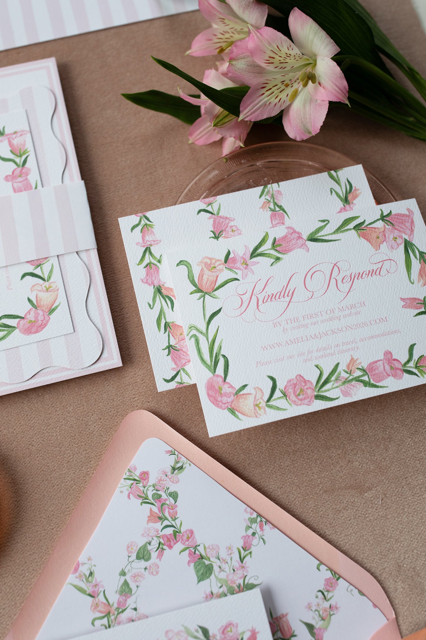Floral invitation card with matching envelope on a pink surface