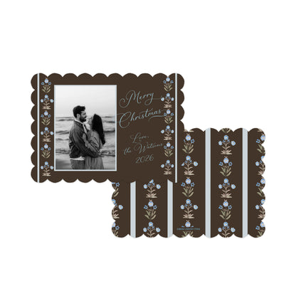 A set of custom scalloped Christmas photo cards in dark brown with blue and beige floral patterns, featuring a black-and-white couple's photo and elegant script text.