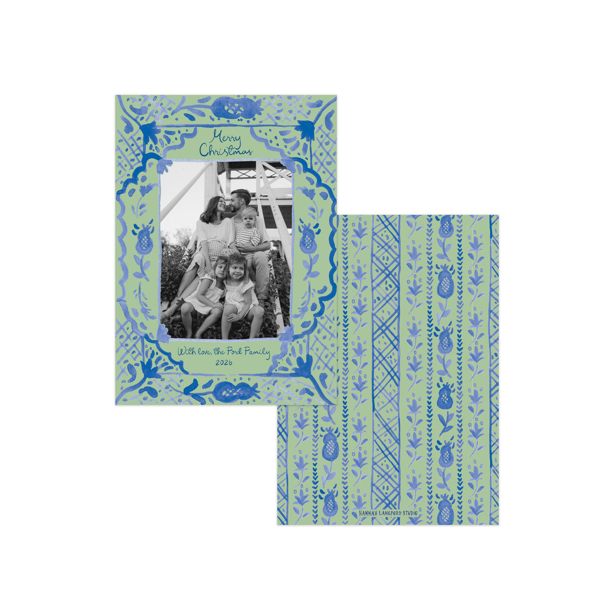 A personalized Christmas photo card set featuring a square front cover and matching envelope. The cards have a light sage green background with blue hand-drawn patterns, including a decorative border around a black-and-white family photo and vertical stripes with pinecone motifs on the envelope.