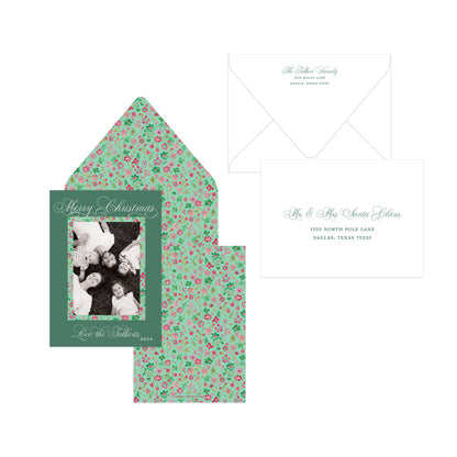 Personalized Christmas invitation suite featuring a dark green front card with a family photo placeholder, a matching floral envelope liner in mint green with pink and red flowers, and a white envelope.