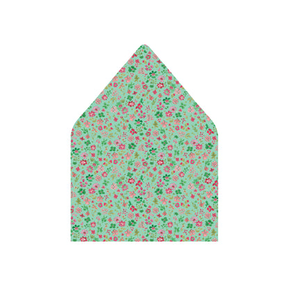A pointed envelope flap featuring a dense, all-over floral print on a mint green background with pink and red flowers and green leaves, shown against a plain white background.