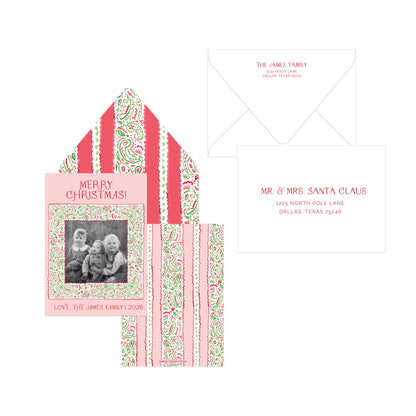 A personalized Christmas card set featuring a pink and green paisley patterned card with a family photo, a matching patterned envelope liner, and a white envelope with printed names.