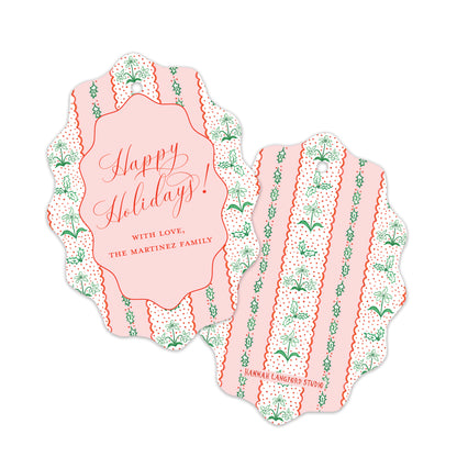 Two scalloped holiday gift tags with a pink and white striped pattern, green botanical motifs, and red text. 
