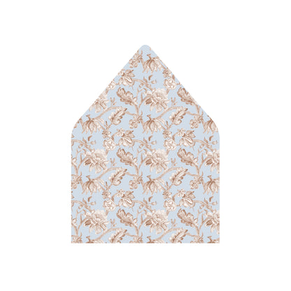 A pointed envelope flap or paper insert featuring a delicate floral toile pattern in beige on a light blue background, shown against a plain white backdrop.