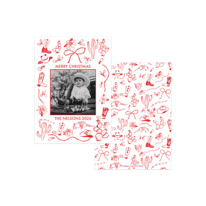 Two white Christmas photo cards with red cowboy-themed line drawings, shown on a clean white background. One card features a custom black-and-white photo of a baby with the text 'MERRY CHRISTMAS THE NELSONS 2026', and the other shows a repeating pattern of the same red illustrations.