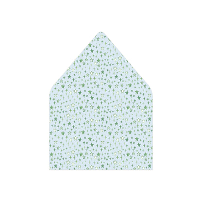 A pointed envelope flap or paper envelope with a light blue background and a repeating pattern of small green star motifs, shown on a plain white background.