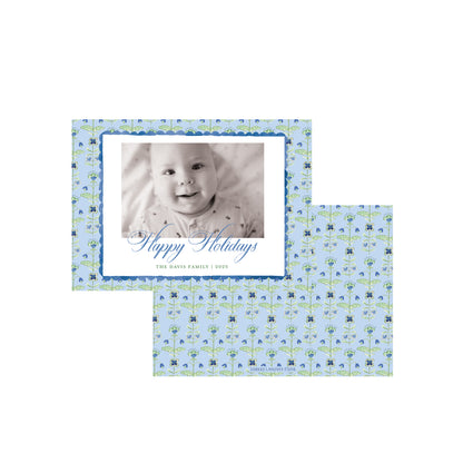 Two personalized holiday photo cards with a light blue floral pattern, one showing a baby photo and the other blank, on a white background.