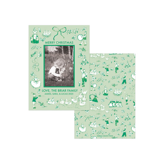 Two personalized Christmas cards with a light sage green background and dark green vintage-style illustrations, shown on a plain white background. One card features a central black-and-white photo frame with the text 'MERRY CHRISTMAS' and 'LOVE, THE BRIAR FAMILY' with names below, while the other shows the full repeating pattern.