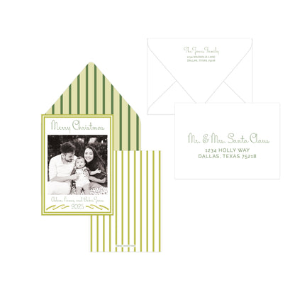 A holiday photo card set with olive green and cream vertical stripes, featuring a main card with a family photo, a striped envelope, and a separate white address card on a plain white background.