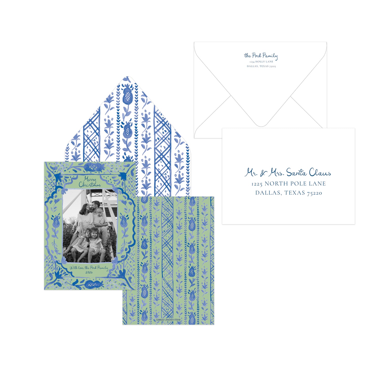 A coordinated stationery set on a white background: a square invitation card with a family photo and blue botanical border, a matching patterned envelope liner, an open white envelope, and a white address card with blue script text.