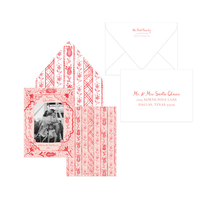 A coordinated stationery set on a white background, including a patterned invitation card with a black-and-white family photo, a matching patterned envelope, and a white card with red script text and address details.