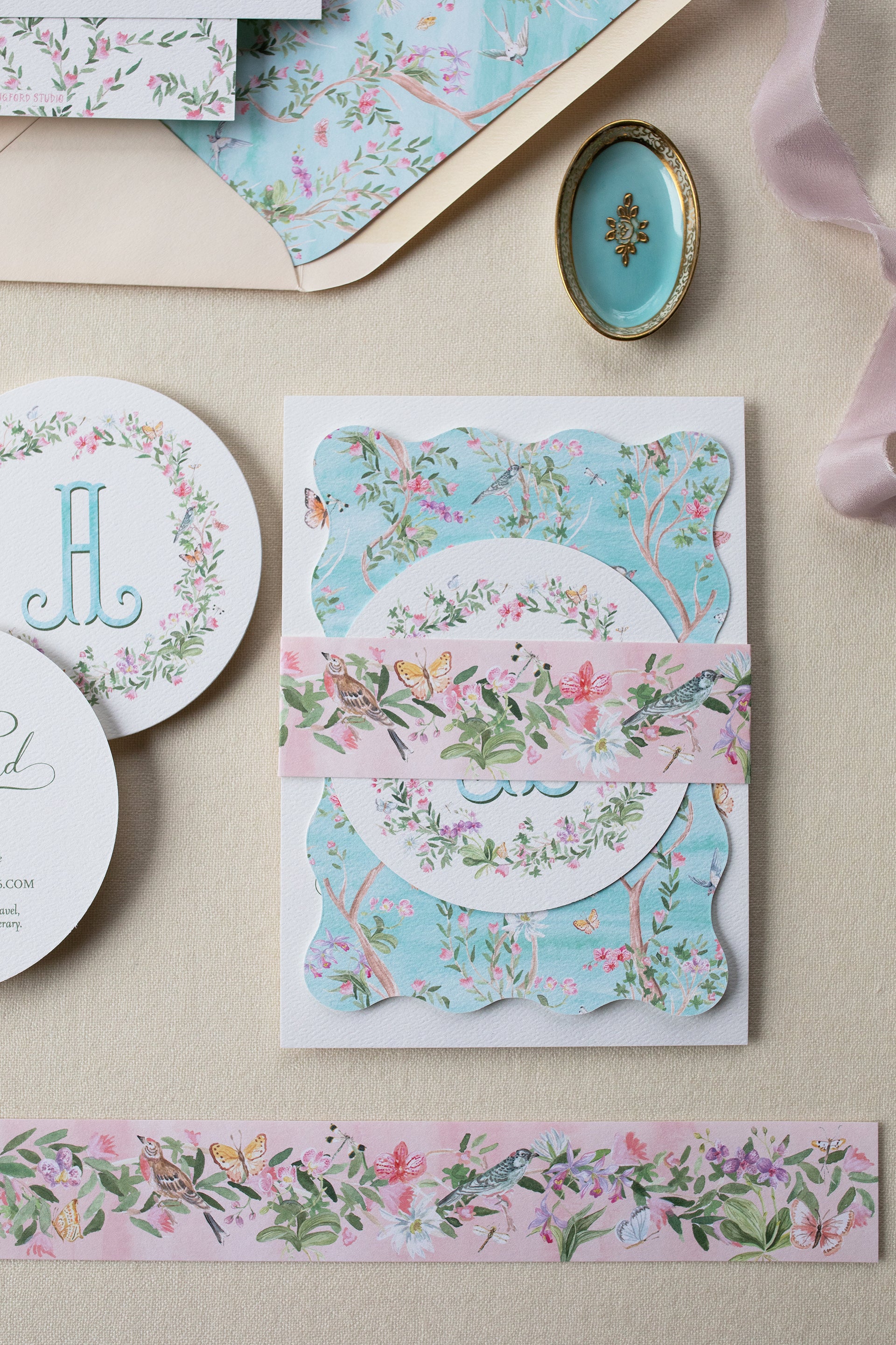 Floral stationery items including a card, envelope, and ribbon on a beige surface.