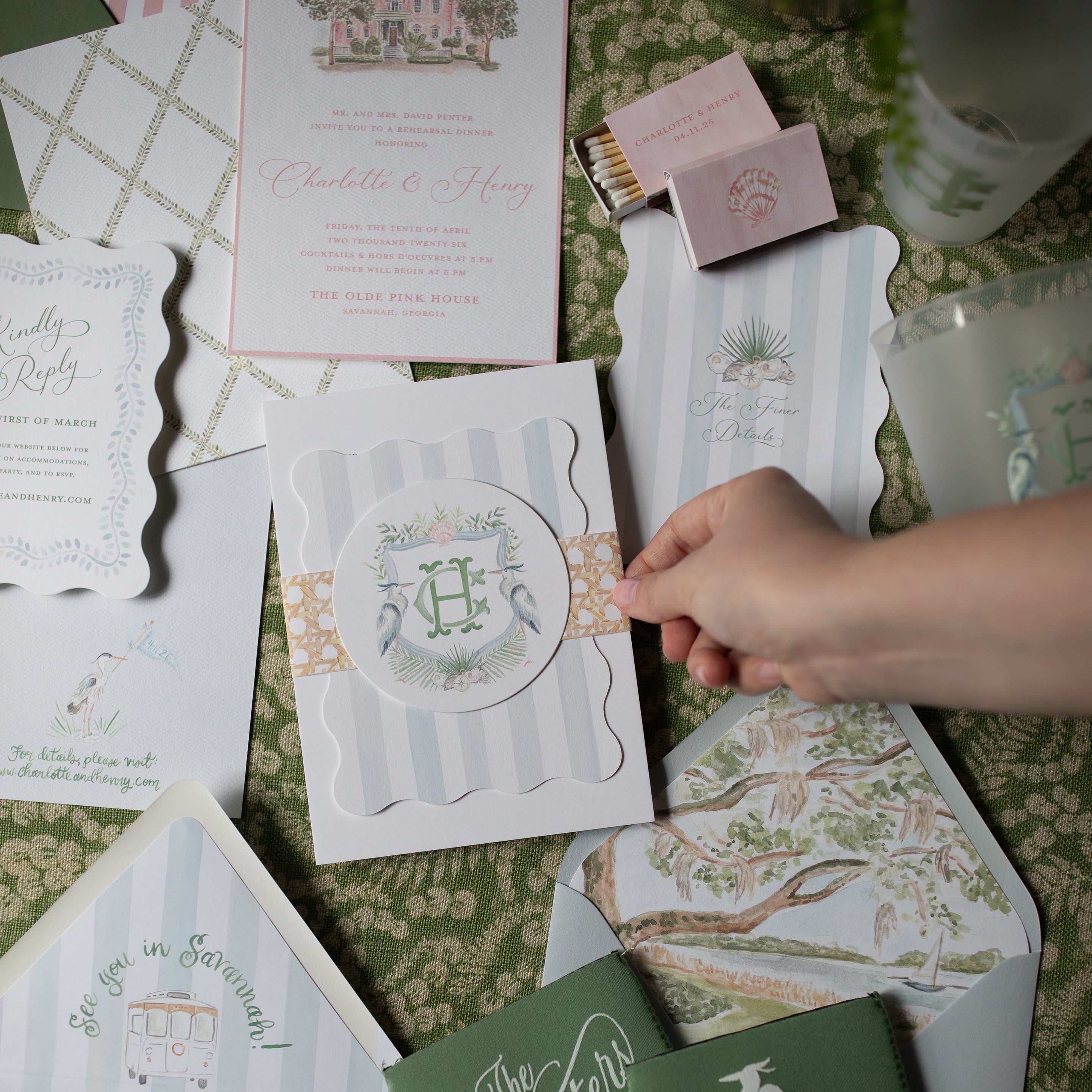 Collection of wedding invitations and stationery items on a green patterned surface.