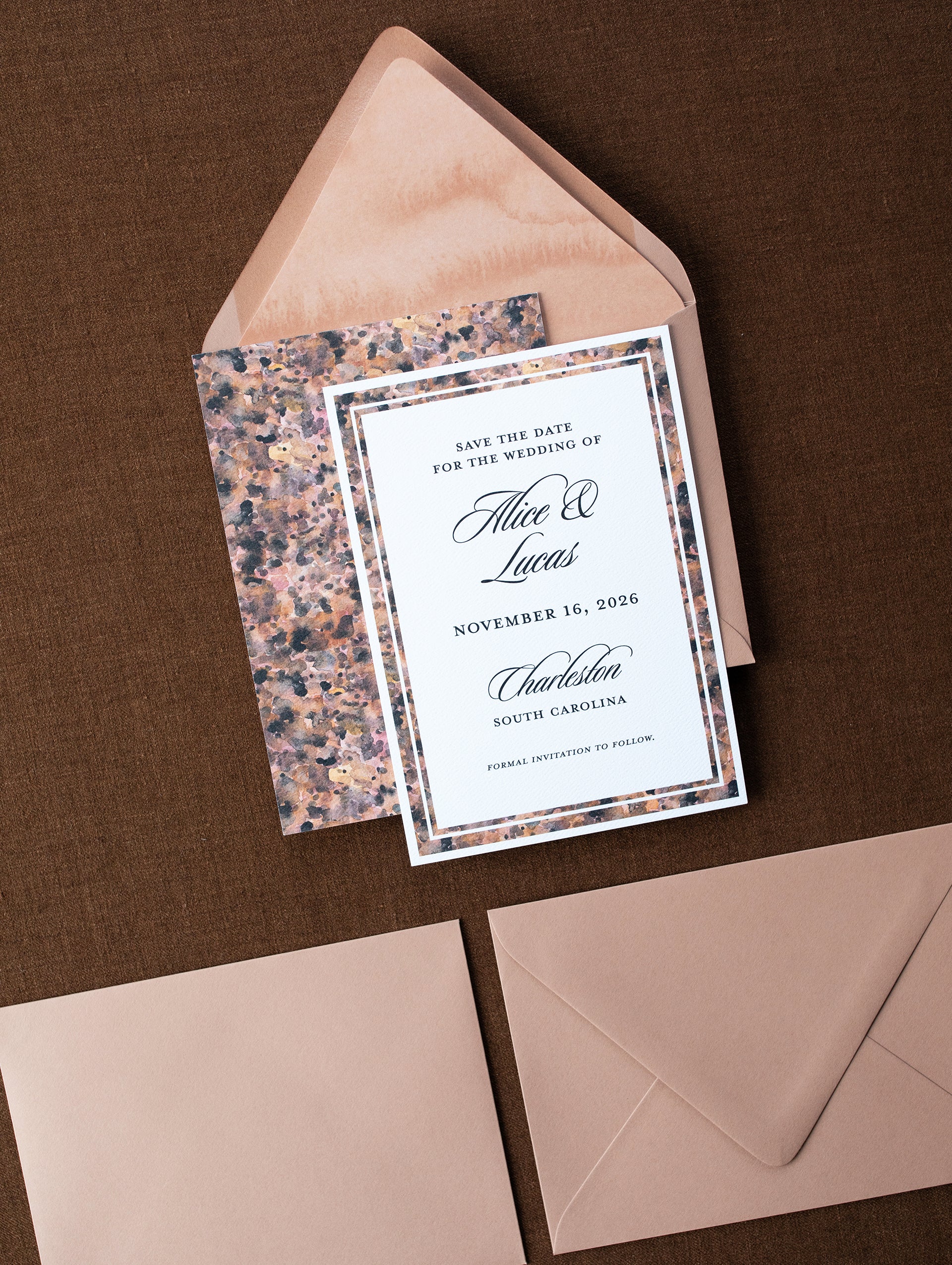 Wedding save the date card with a patterned envelope on a brown background
