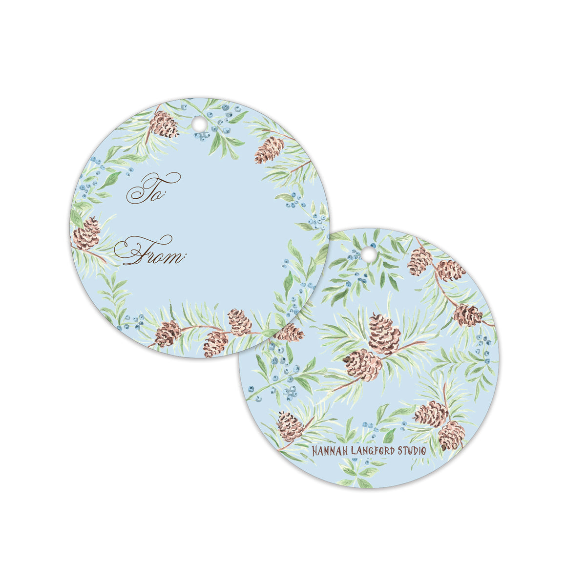 Two round hanging gift tags with a light blue background, decorated with a green pine and berry botanical pattern, brown pinecones, and elegant cursive text.