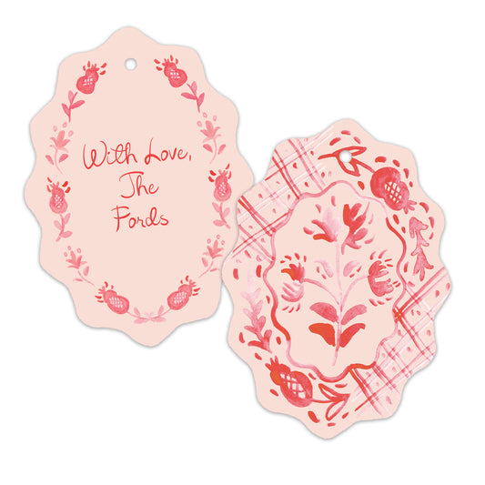 Two decorative gift tags with scalloped edges on a white background. One tag is pale pink with red script reading 'With Love, The Fords' surrounded by floral and pomegranate illustrations.