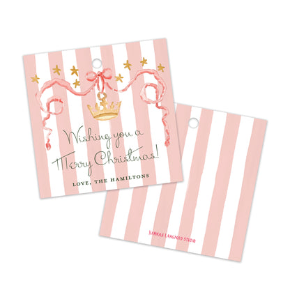 Two personalized Christmas gift tags with pink and white vertical stripes, featuring a gold crown, ribbon, and stars. 