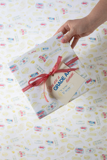 hand holding present wrapped in paper with butter illustrations on it