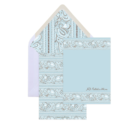Light blue patterned card and envelope with decorative border on a white background