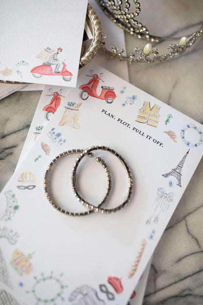 Earrings on a decorative card with illustrations and text