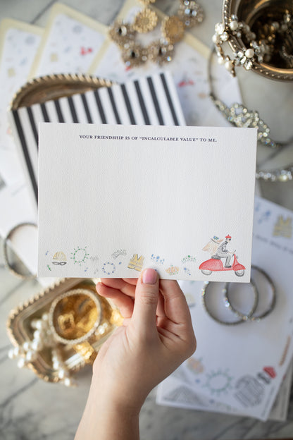 Hand holding a card with decorative elements on a surface with jewelry