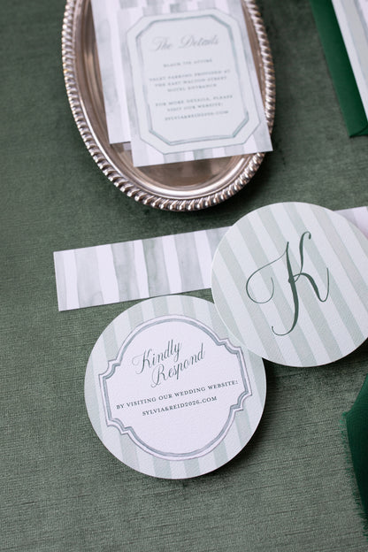 Wedding invitation cards with RSVP and website information on a green surface