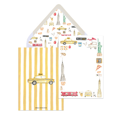 A set of NYC-themed stationery with hand-illustrated motifs including a yellow cab, the Empire State Building, and other New York City landmarks, displayed on a striped background with a blank white envelope.