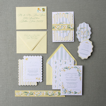 Collection of yellow and white wedding invitations on a gray surface