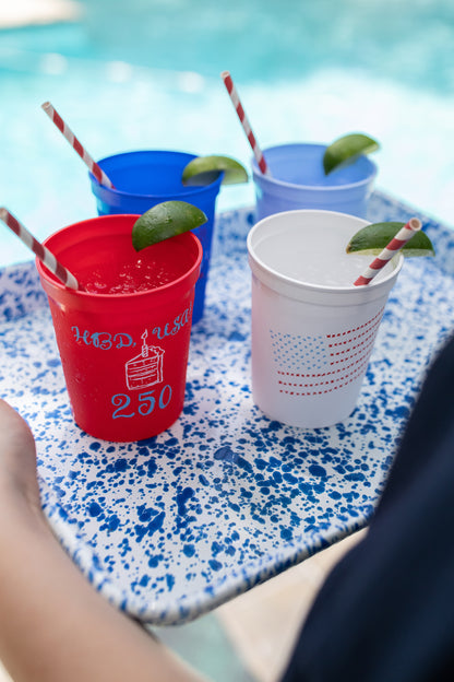 Colorful plastic cups with straws and lime wedges on a poolside table.