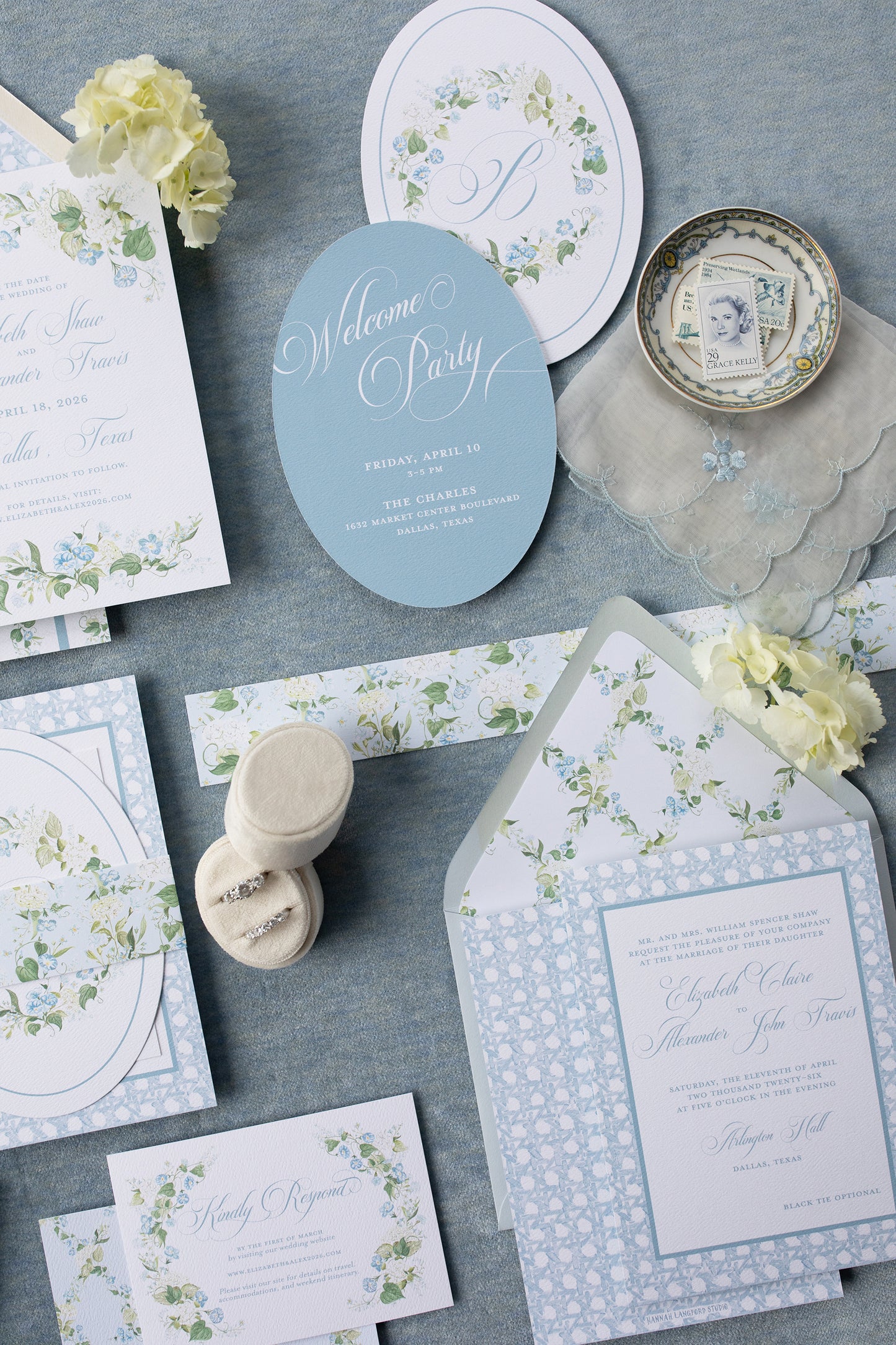 Collection of wedding invitations and stationery items on a gray surface with floral designs.