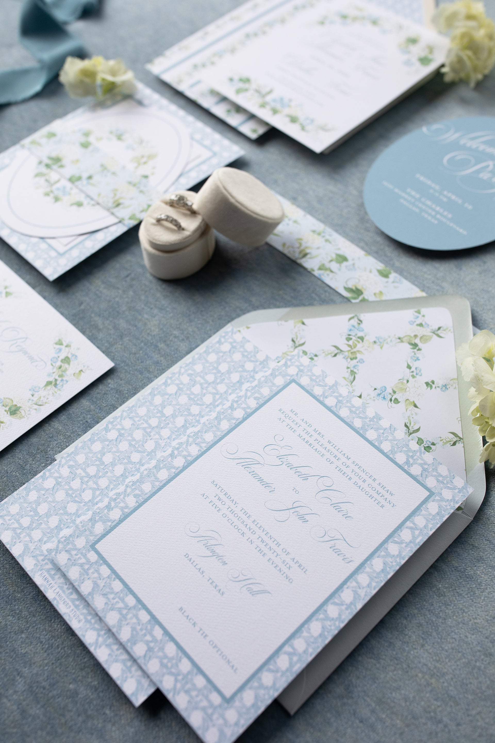 Wedding invitation set with floral designs on a gray surface