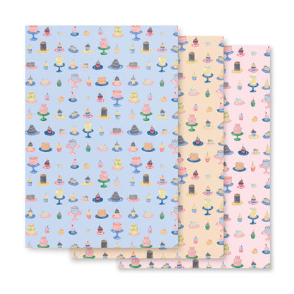 A set of three sheets of vintage-inspired gift wrap featuring colorful party cakes on a blue and pink background.